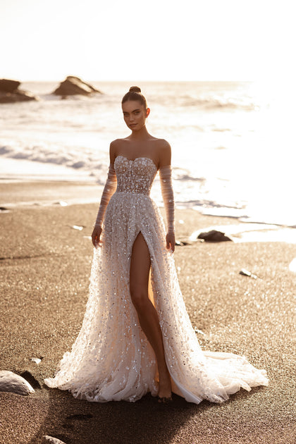 The Reem wedding gown with a sequin corset and long train captivates with 3D floral texture and romantic seaside sparkle.