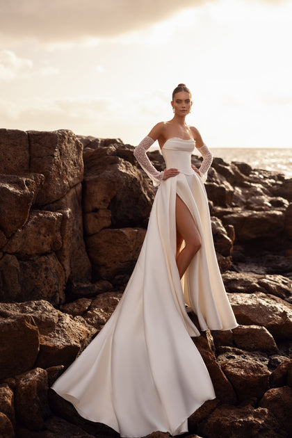 The Sarabi wedding gown with a structured corset and pearl-studded gloves highlights feminine elegance and luxury.