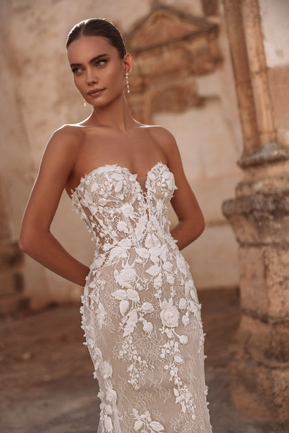 The Sarifa lace wedding dress with dramatic train and floral details exudes luxury and modern romance.