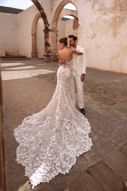 The Sarifa mermaid wedding dress with a corset bodice and floral lace embroidery beautifully accentuates the bride’s figure.