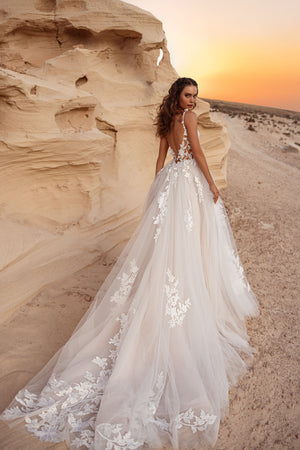 The Zafira wedding dress with an open back and a long tulle train adorned with 3D floral lace appliqués.