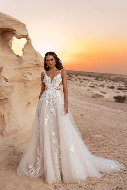 The Zafira wedding dress with a plunging V-neckline and 3D floral lace appliqués shines beautifully against the desert sunset backdrop.